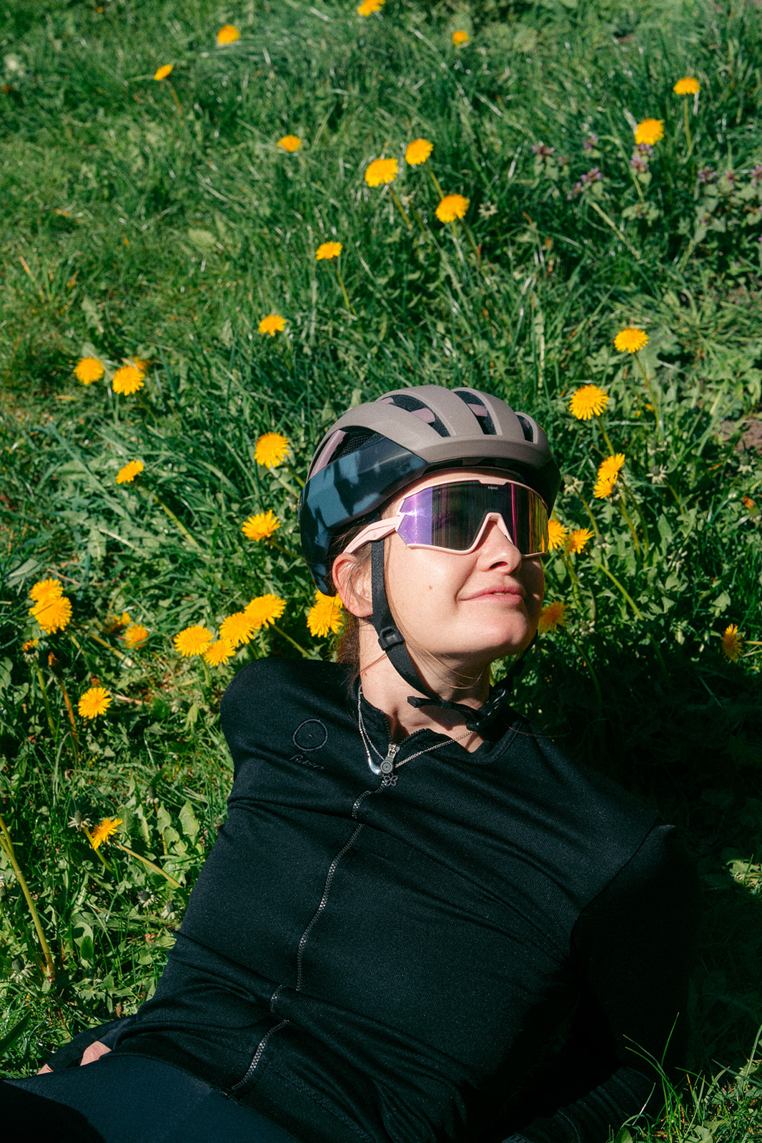 Weronika w kasku i okularach rowerowych odpoczywająca na trawie wśród żółtych kwiatów